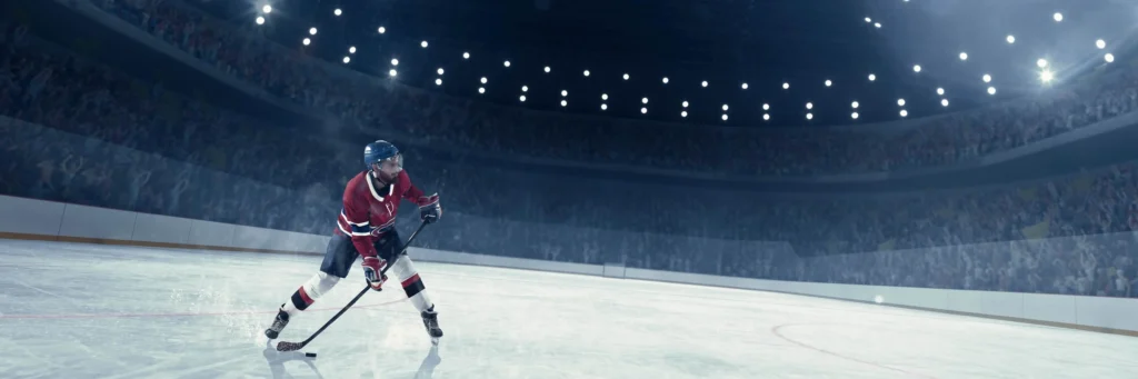Vue d'un joueur de hockey en uniforme sur la patinoire d'un grand amphithéâtre tenant son bâton durant un entraînement.