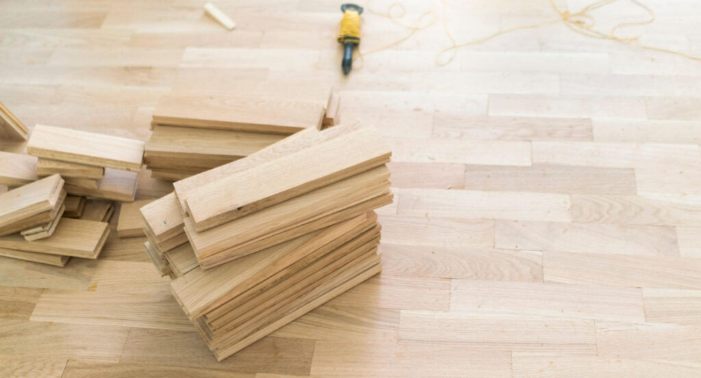 Gros plan sur des lattes de bois franc en cours d'installation montrant la texture naturelle et le savoir-faire de transformation.