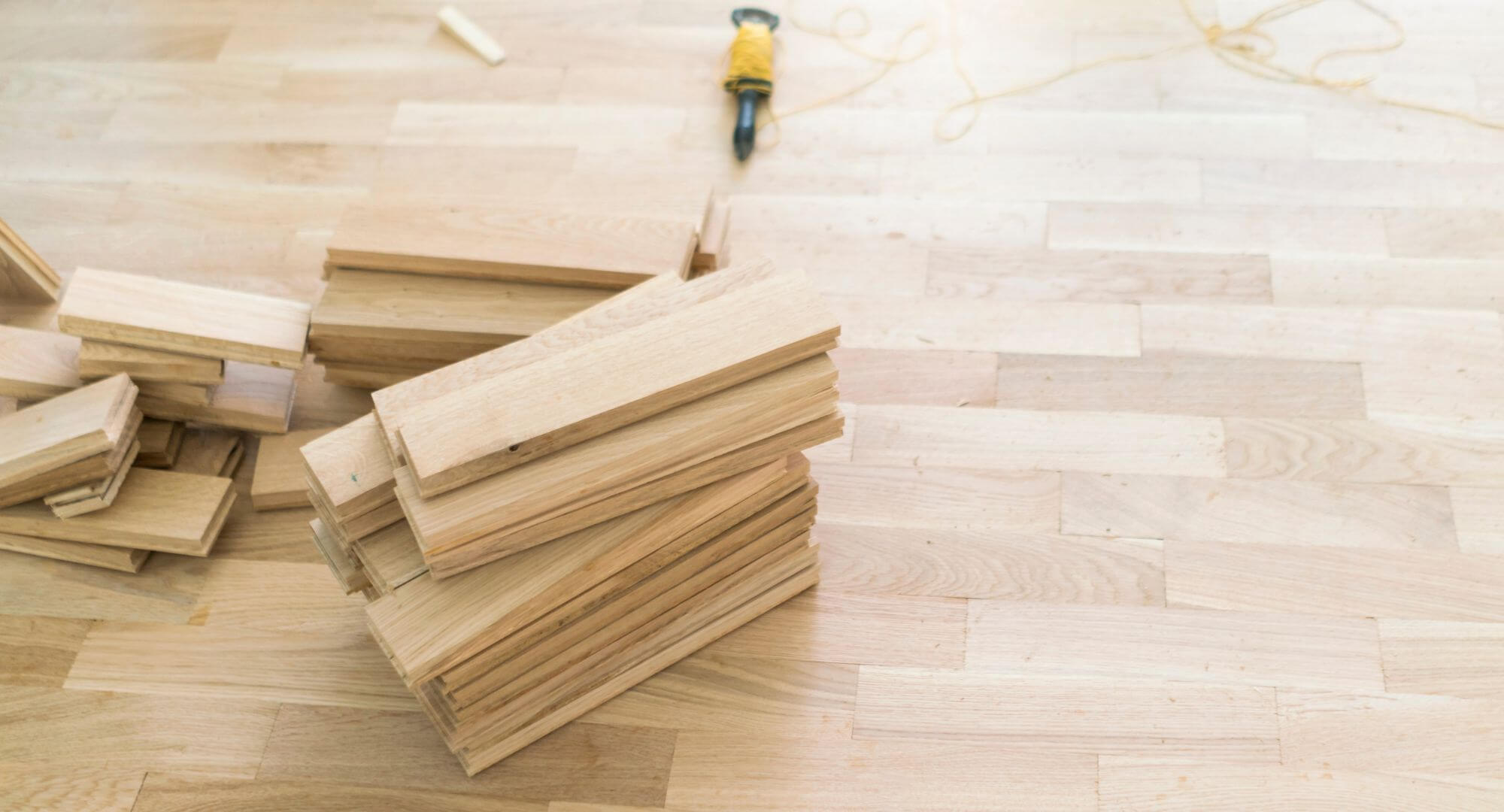 Gros plan sur des lattes de bois franc en cours d'installation montrant la texture naturelle et le savoir-faire de transformation.